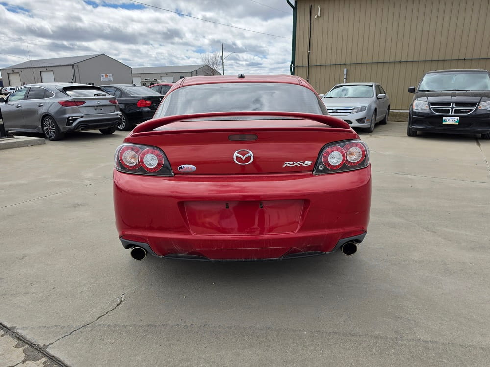 Red Mazda RX-8 sports car parked in Pembina Valley dealership lot.