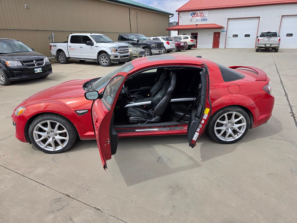 Red sports car with open door, showcasing interior at Pembina Valley Auto dealership.