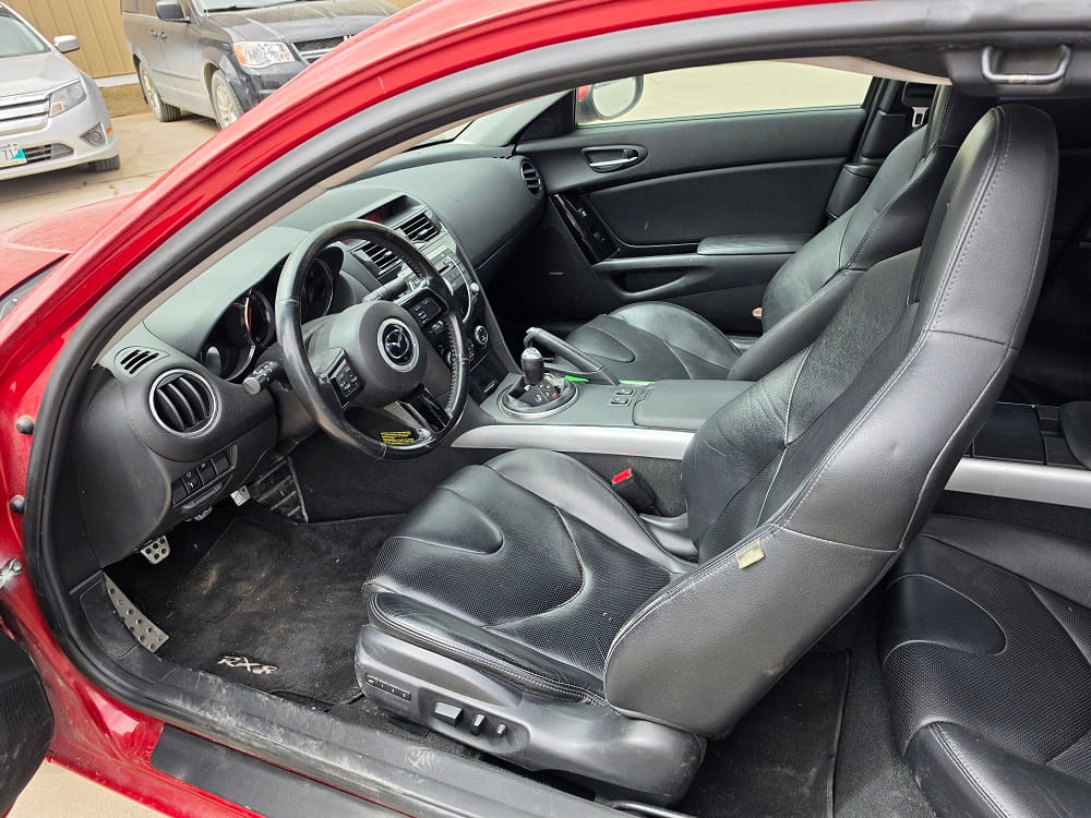 Interior of a Mazda RX-8 sports car showing black leather seats and dashboard.