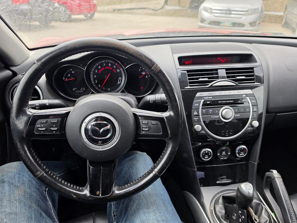 Interior view of Mazda dashboard and steering wheel in a vehicle.
