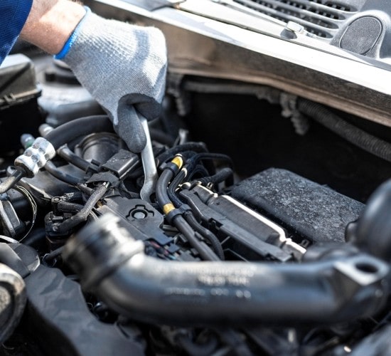 Automotive mechanic inspecting car engine with tools.