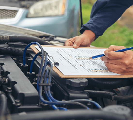Technician inspecting car engine with clipboard for auto service at Penguin Auto.