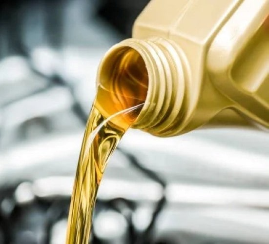 Fresh engine oil being poured during auto maintenance at Penguin Auto.
