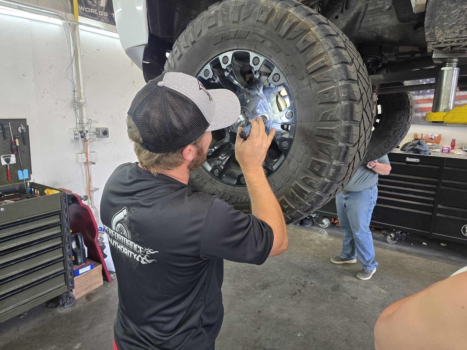 Technician inspecting and repairing a large off-road tire at Performance Authority.