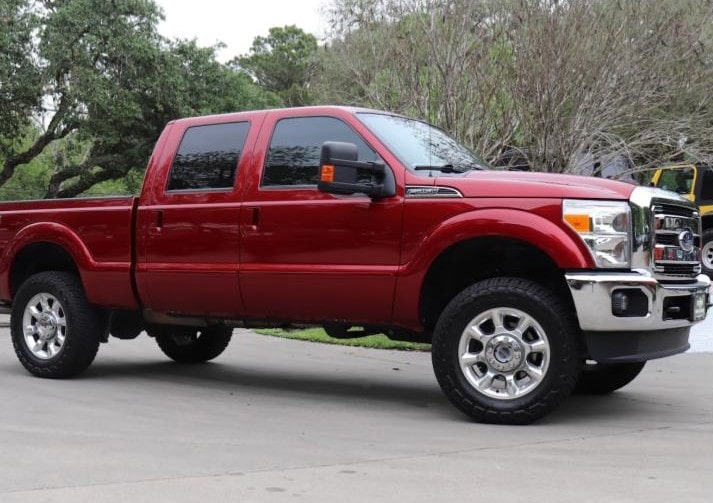 Red Ford Super Duty truck parked outdoors with trees in the background.
