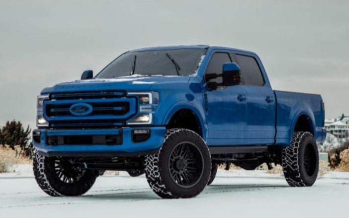 Blue Ford truck with off-road tires on snowy terrain at Performance Authority.
