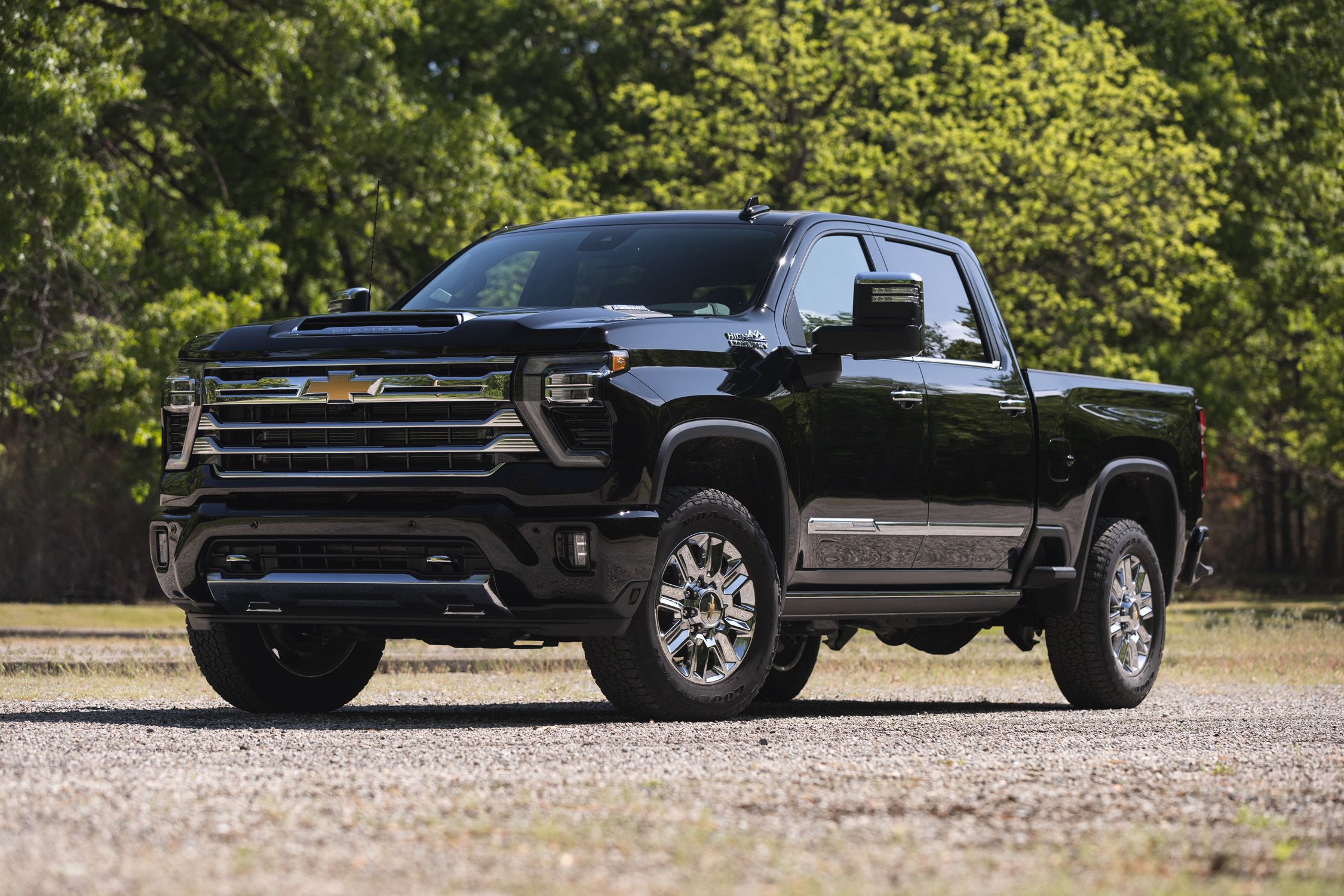 Black Chevrolet Silverado pickup truck parked outdoors with green trees in background.