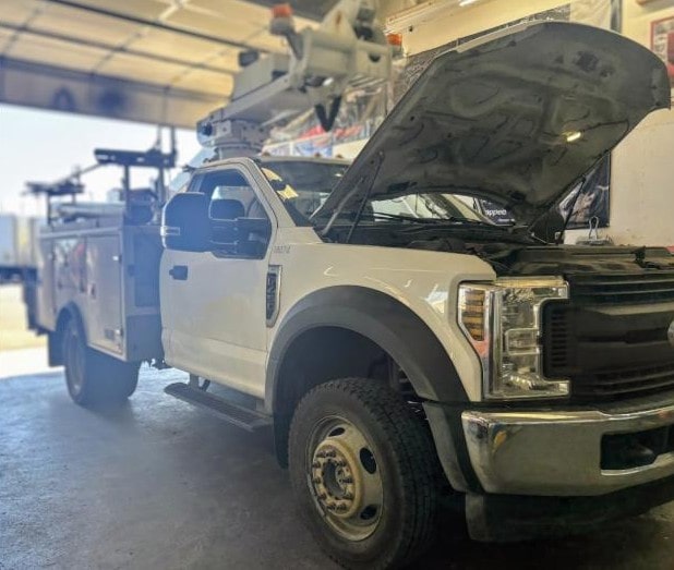 Service truck with open hood and equipment for vehicle maintenance.