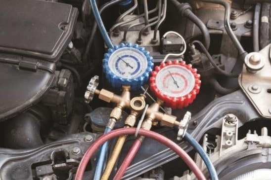 HVAC service tools with gauges and hoses on car engine for performance tuning.