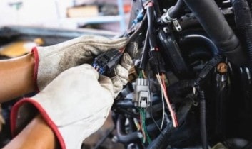 Skilled technician repairing vehicle wiring at Performance Authority.