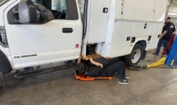 Service truck maintenance technician inspecting vehicle.