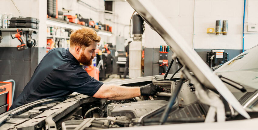 Skilled mechanic inspecting vehicle engine at Performance Authority in Bend.