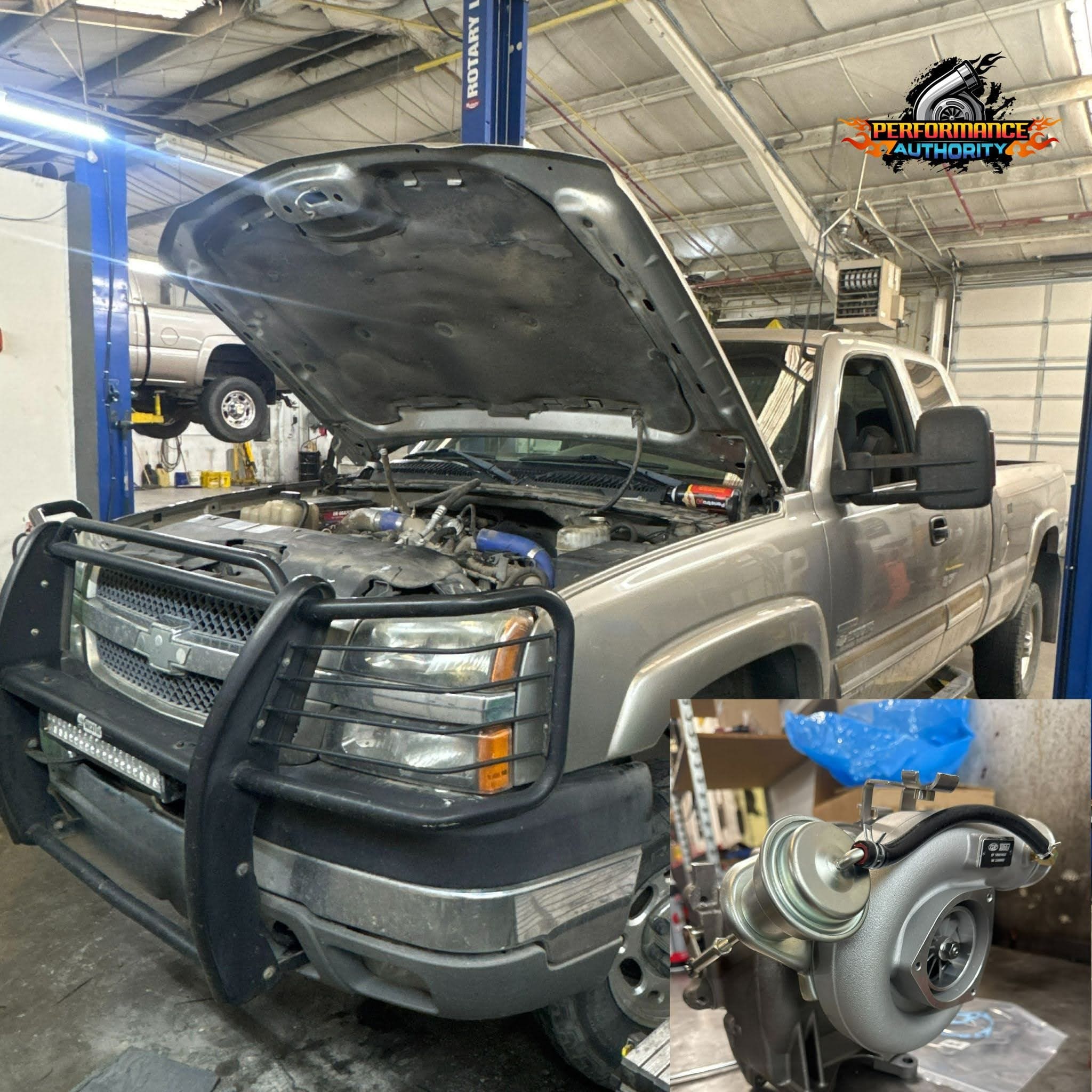 Silver pickup truck with open hood and turbocharger component in workshop.