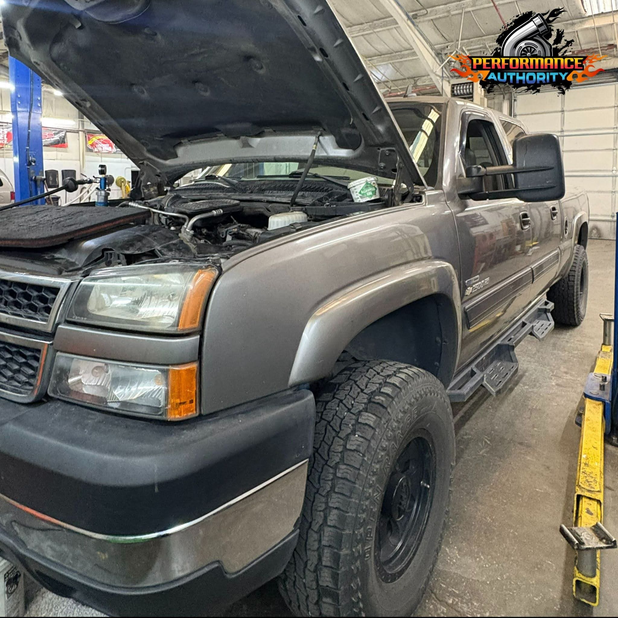 Custom truck repair at Performance Authority with engine hood open in workshop.
