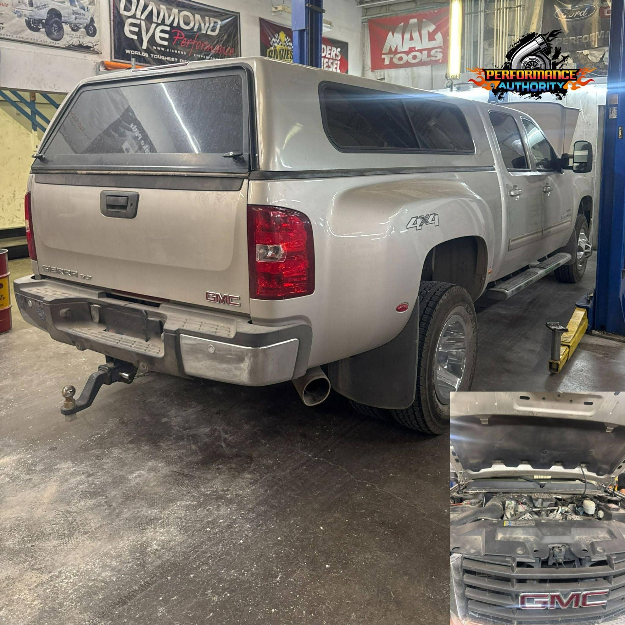 GMC Sierra pickup truck in repair shop with engine work in progress.