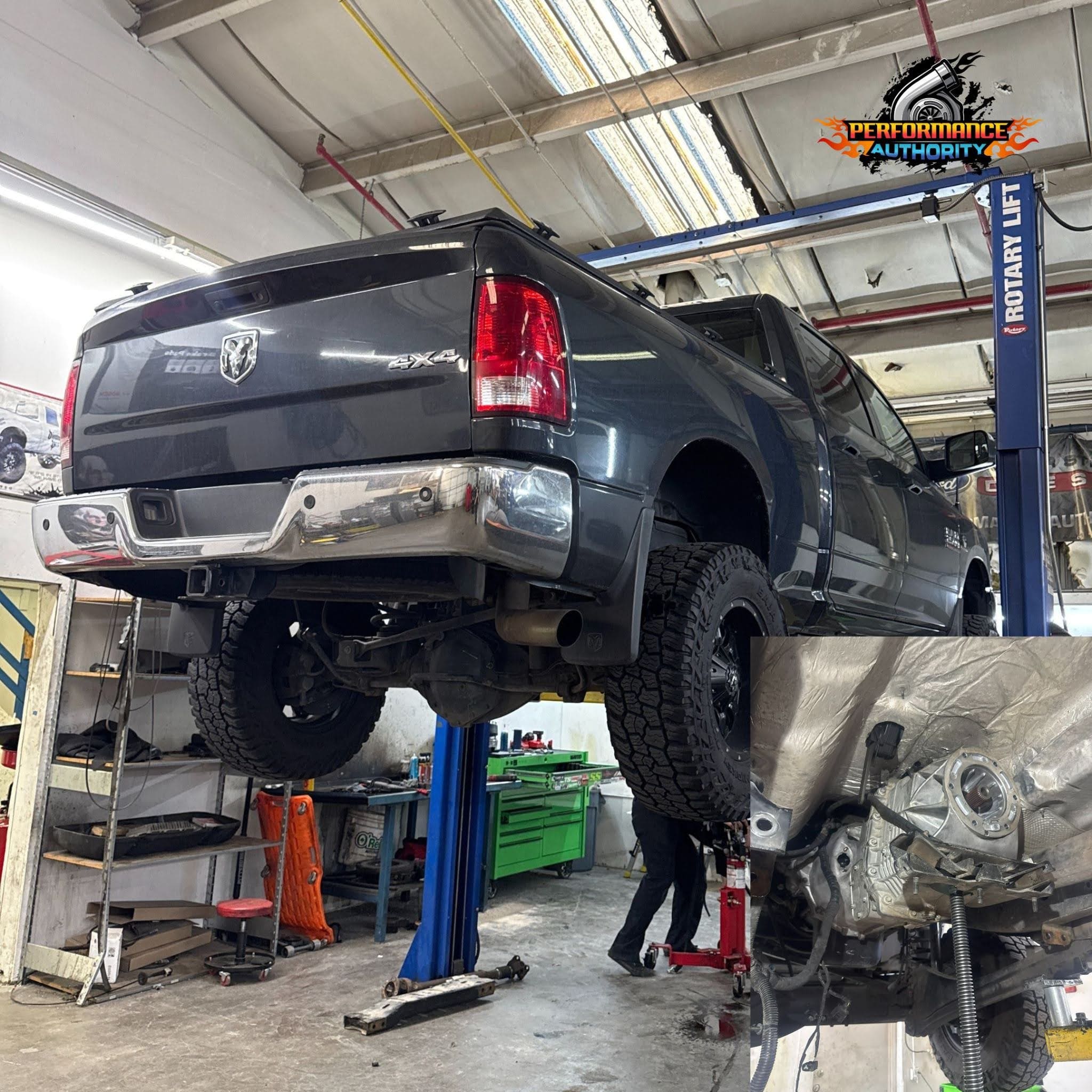Elevated dark gray RAM truck on hydraulic lift at Performance Authority.