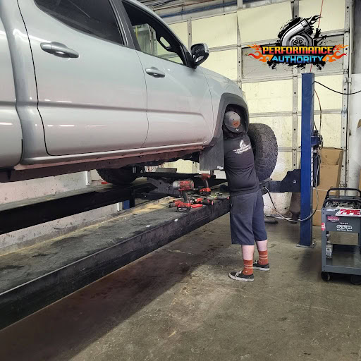 Automotive technician inspecting a vehicle lifted on a hydraulic lift at Performance Authority.