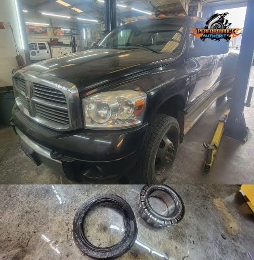 Black Dodge Ram vehicle in auto repair shop with wheel bearing parts below.