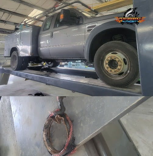 Silver pickup truck on lift in auto repair shop for maintenance or repair.