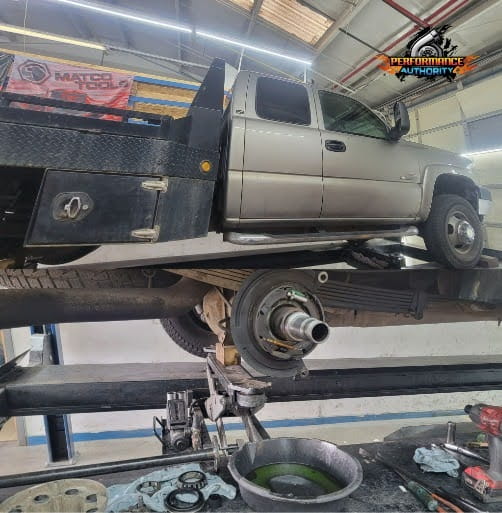 Silver pickup truck on lift in auto repair shop for maintenance or repair.