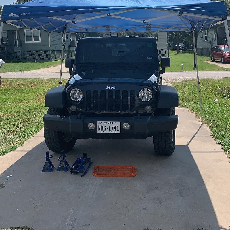 Jeep vehicle lifted for repair with jack stands and tools.