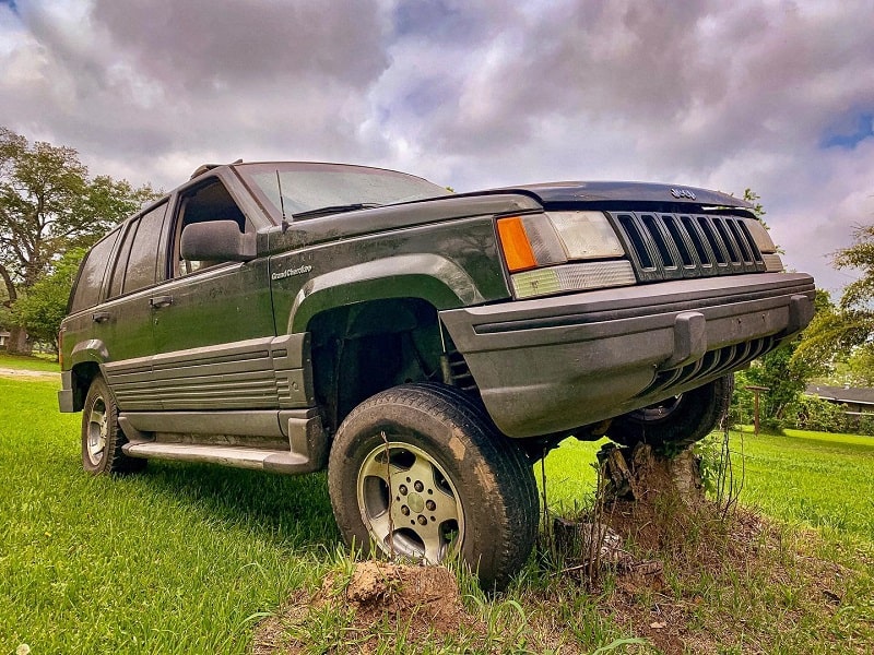 Jeep Grand Cherokee lifted on a tree stump for repair or inspection at Phantom Auto Repair.