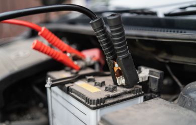 Jump-starting car battery with jumper cables for vehicle repair.