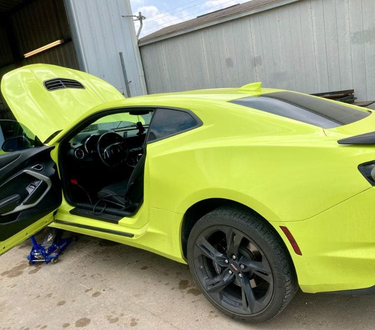 Bright yellow sports car with open door at Phantom Auto Repair shop.