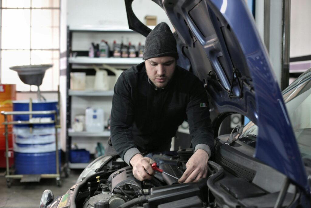 Skilled mechanic inspecting car engine in auto repair shop.