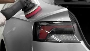 Close-up of a professional polishing process on a car's tail light and rear panel.