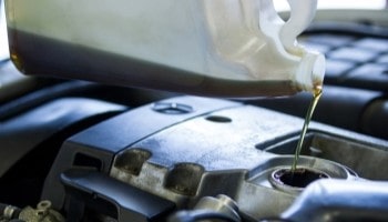 Oil being poured into a car engine for maintenance at Philips Auto & Tires.