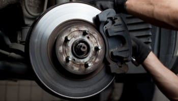 Brake disc and caliper being serviced on a vehicle.