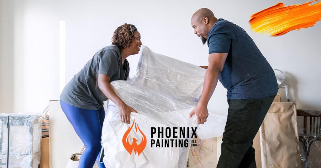 Two people moving furniture for painting.