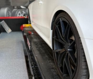Close-up of a white car's black alloy wheel during professional auto care service.