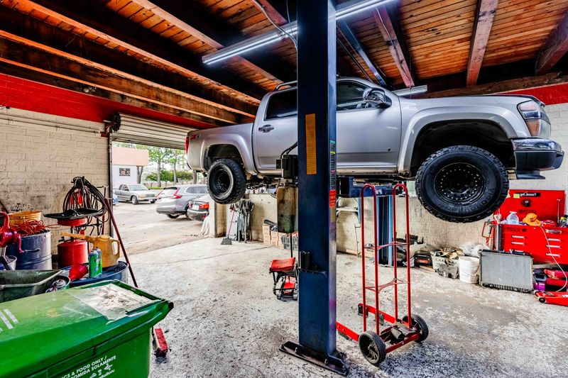 Auto repair shop with a lifted pickup truck on a hydraulic lift for maintenance and repairs.