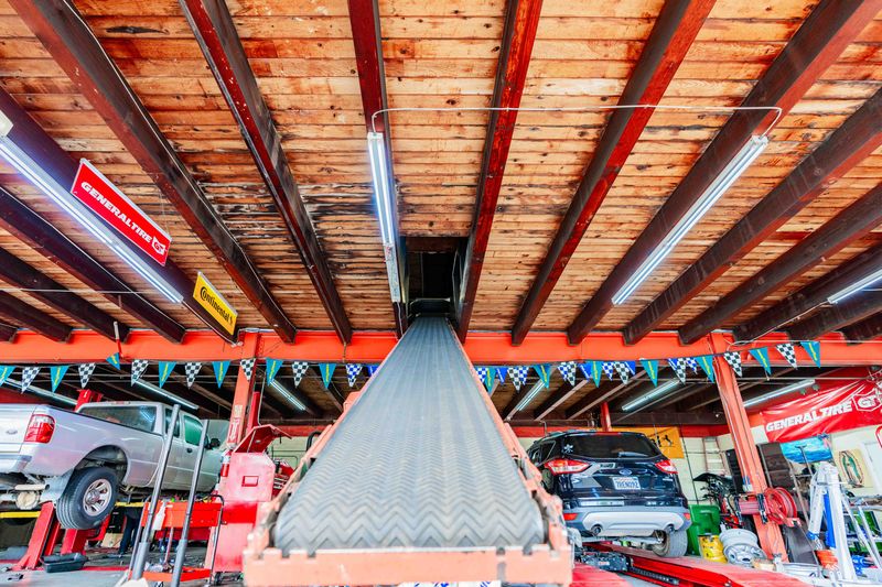 Auto repair shop with vehicle lift and cars in service bay.