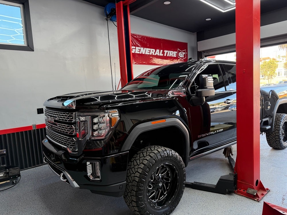 Heavy-duty truck lifted on a hydraulic lift at Pittstop Auto Care. Expert auto repair and tire servi.