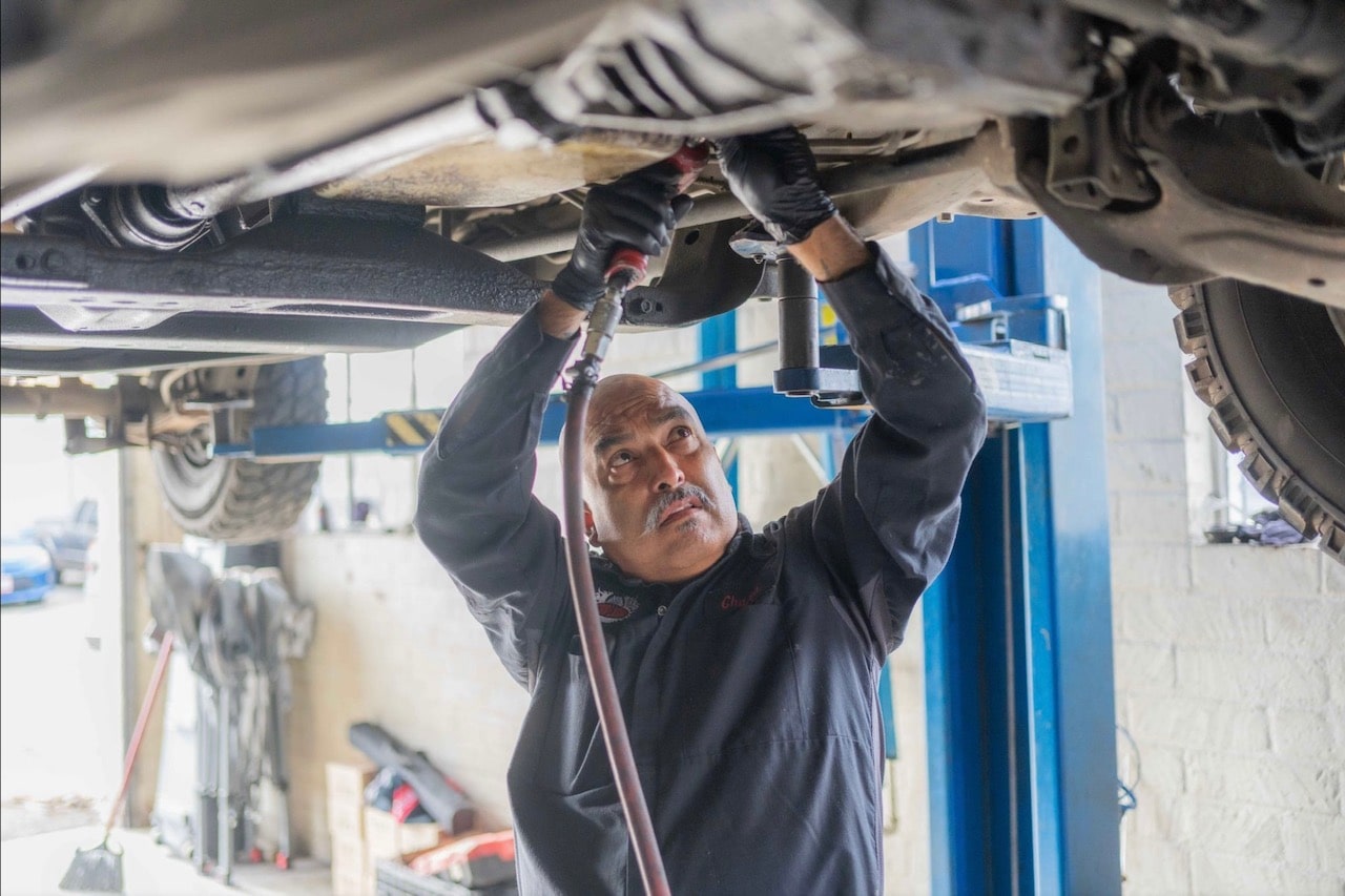 Auto mechanic inspecting vehicle underside at Pittstop Auto Care.