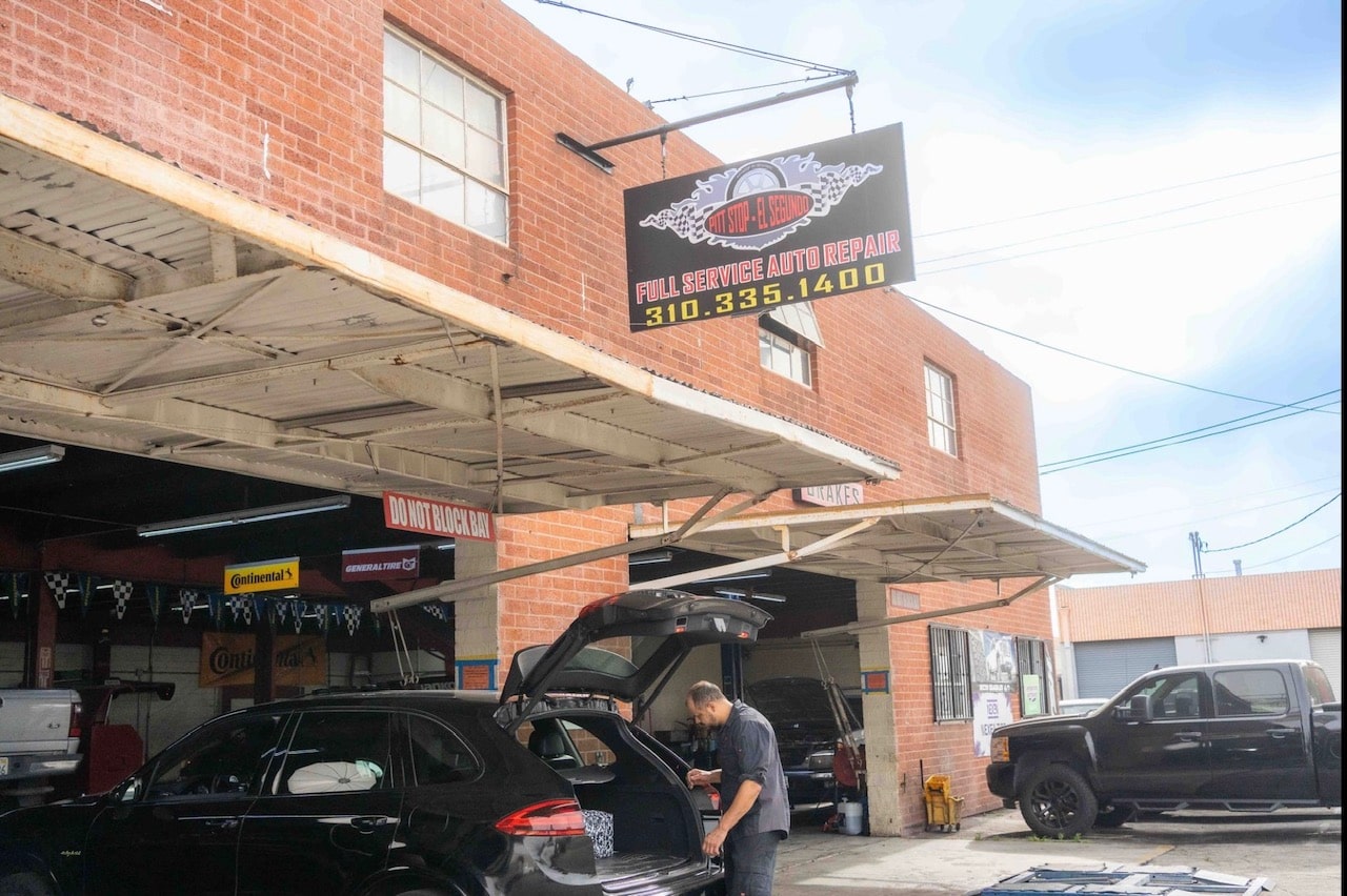 Auto repair shop exterior with technician working on a vehicle in Pittstop Auto Care.