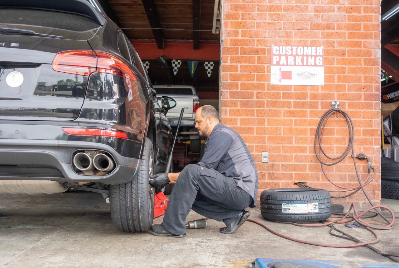 Technician changing a car tire at Pittstop Auto Care, auto repair and maintenance.