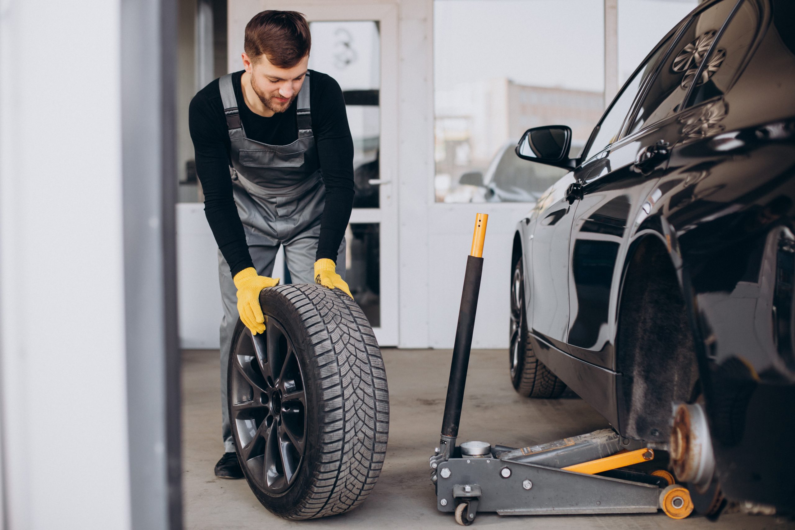 Skilled technician changing a car tire at Pittstop Auto Care shop.