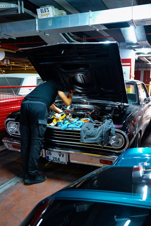 Auto mechanic inspecting car engine at Johnny’s Automotive repair shop.