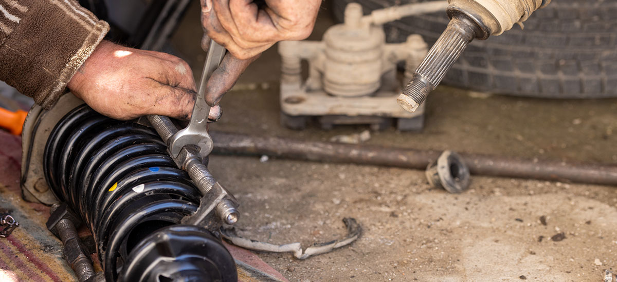 Mechanic inspecting vehicle suspension components for issues.