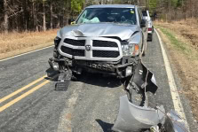Silver SUV with front-end damage after collision on rural road.