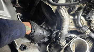 Mechanic inspecting engine components during vehicle maintenance.
