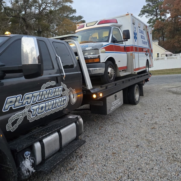 Emergency towing service with flatbed truck for vehicles and ambulances. Reliable roadside assistanc.