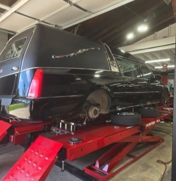 Black limousine on a hydraulic lift at POPS FULL SERVICE.