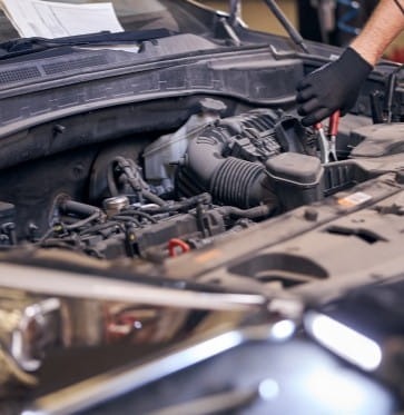 Technician inspecting car engine for maintenance or repair.