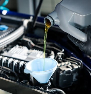 Engine oil being poured into a car engine during oil change.