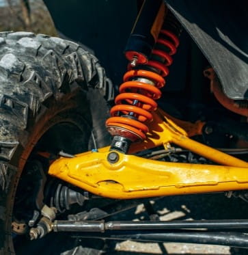 Close-up of off-road vehicle suspension with coil spring and shock absorber.